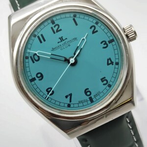 Pode incluir: Um rel&oacute;gio prateado com mostrador turquesa e algarismos pretos. O rel&oacute;gio apresenta o texto "JAEGER LECOULTRE CLUB" e "SWISS MADE". Possui uma pulseira de couro verde escuro.