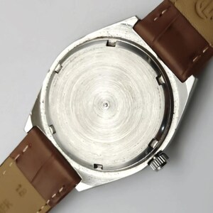 K&ouml;nnte beinhalten: Eine silberfarbene Armbanduhr mit braunem Lederarmband. Das Uhrengeh&auml;use ist rechteckig mit rundem Boden. Das Armband ist mit Federstegen am Geh&auml;use befestigt. Die Uhr hat eine silberfarbene Krone.