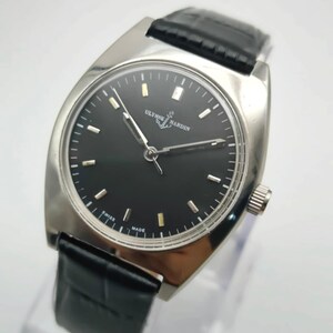 Puede incluir: Un reloj de pulsera Ulysse Nardin plateado con esfera negra y correa de cuero negro. El reloj presenta marcadores de hora y agujas plateadas, y el nombre de la marca se muestra en la esfera. El reloj est&aacute; marcado "Swiss Made".