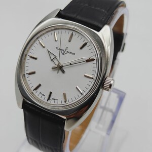 May include: A silver-toned wristwatch with a white face and black leather band. The watch face features the brand name "ULYSSE NARDIN" and the words "SWISS MADE". The watch has a classic design.