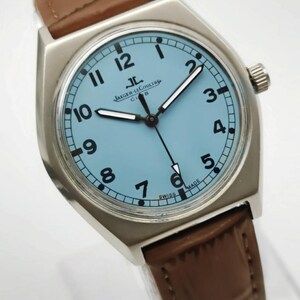 K&ouml;nnte beinhalten: Eine silberfarbene Armbanduhr mit hellblauem Zifferblatt und braunem Lederarmband. Das Zifferblatt zeigt schwarze Ziffern und Zeiger, mit der Marke "JAEGER-LECOULTRE" und "SWISS MADE". Die Uhr hat ein rechteckiges Geh&auml;use.