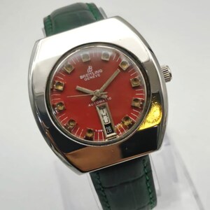 May include: A vintage Breitling Geneve automatic watch with a red dial and a date display. The watch has a silver-tone case and a green leather strap. The watch face features gold-tone hour markers and hands.