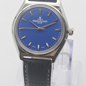 May include: A silver-toned Jaeger-LeCoultre Club watch with a blue dial and a black leather strap. The watch face features silver-toned hour markers and hands. The words "JAEGER-LECOULTRE CLUB" are printed on the dial.