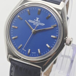 May include: A stainless steel Jaeger-LeCoultre Club watch with a blue dial and a black leather strap. The watch features silver hands and markers, and the dial is marked with "JAEGER-LECOULTRE CLUB". The watch has a round face and a textured leather strap.