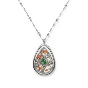 Peut inclure: Collier pendentif argenté avec un pendentif en forme de goutte d'eau. Le pendentif présente un motif orné avec des feuilles orange et jaunes, une pierre verte et un fond blanc. La chaîne du collier est délicate et argentée.