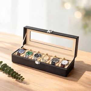 May include: A rectangular black watch display case with white contrast stitching and a clear glass lid. The interior is lined with beige fabric and features six individual compartments, each containing a wristwatch with a unique dial color.