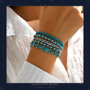 Könnte beinhalten: Mehrere türkisfarbene und silberne Armbänder. Die Armbänder zeigen Türkissteine, kleine Perlen und verzierte Silbermuster. Die Armbänder werden an einem Handgelenk getragen, vor einem weißen Hemd. Der Text "VELOSSA BY BERNIE" und "Curated Elegance for Everyday Living" ist enthalten.