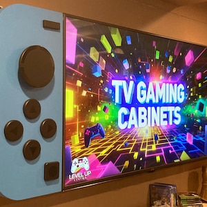 May include: A custom TV gaming cabinet designed to resemble a game controller. The cabinet is light blue and red, with black buttons and a screen displaying "TV Gaming Cabinets". The "Level Up Living" logo is visible.