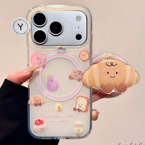 May include: Clear phone case with a variety of food-themed charms, including a donut, croissant, and bread, with smiling faces. The case has a pink circle design and the text "Regard nothing in matters of love and food."