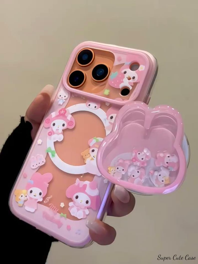 May include: Pink phone case with a clear back and a pop-up grip. The case features cartoon characters and a clear, pink grip filled with small figures. The text "Super Cute Case" is visible on the bottom right.
