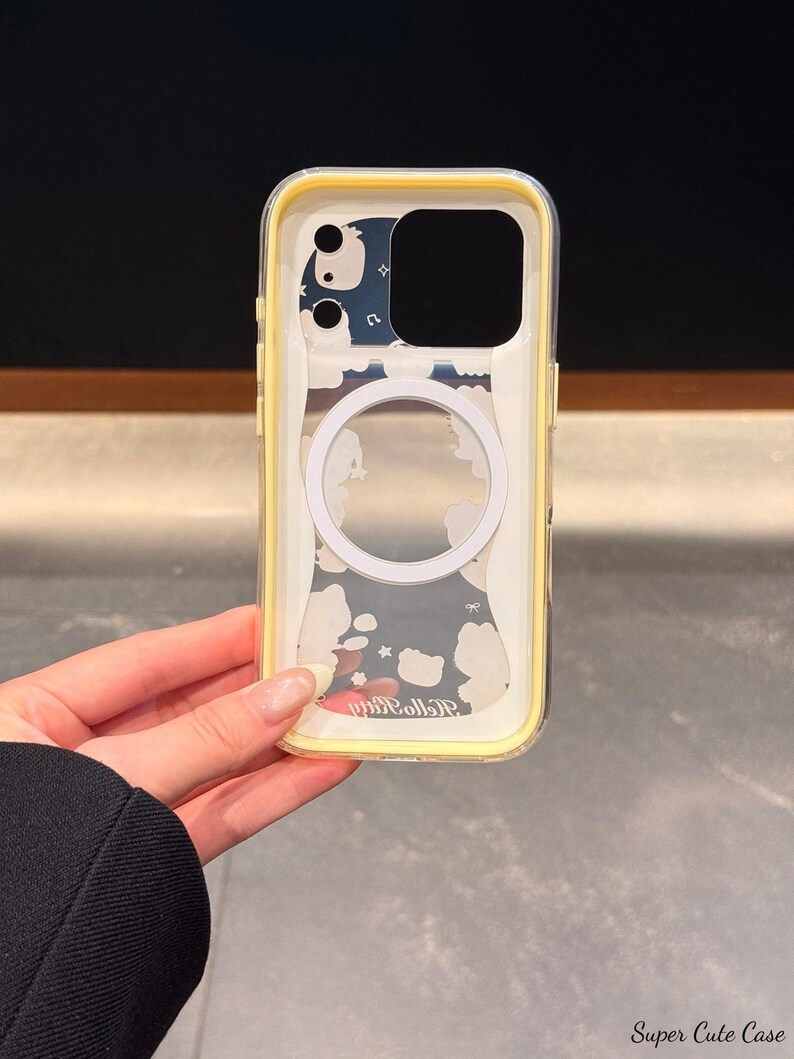 Peut inclure: Coque de t&eacute;l&eacute;phone transparente avec un bord jaune. La coque pr&eacute;sente un cercle blanc et un motif de nuages blancs et d'&eacute;toiles sur fond bleu. Le texte "Hello Kitty" est visible en bas.