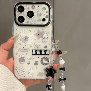 Pode incluir: Capa de telefone transparente com interior branco com coelhos de desenho animado, estrelas e a palavra "Love". Uma al&ccedil;a de contas com estrela preta, la&ccedil;os e contas est&aacute; presa. A capa tem o texto "Super Cute Case."