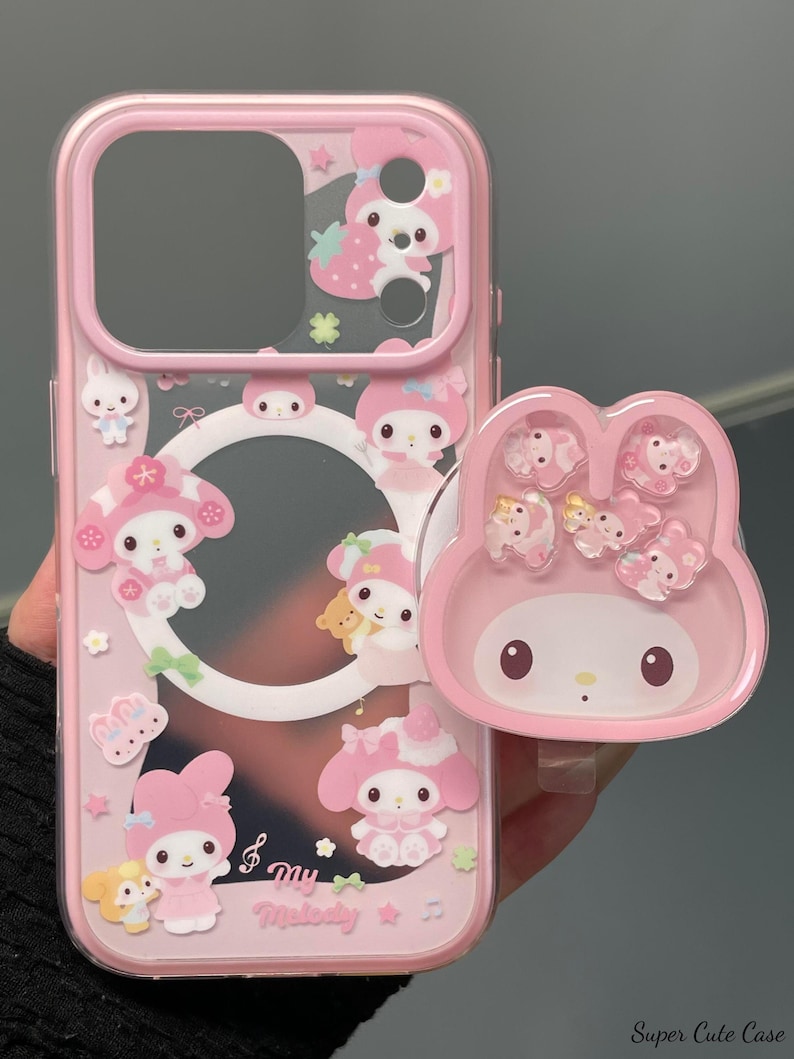 May include: Pink phone case with a clear center and a matching pop-up grip. The case features cartoon characters, strawberries, and stars. The pop-up grip has a My Melody design. The text "Super Cute Case" is visible in the bottom right corner.