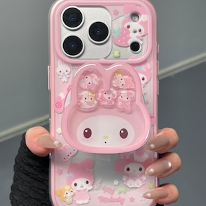 May include: Pink phone case featuring a My Melody design. The case has a clear border and includes a 3D My Melody character and other decorative elements. The text "Super Cute Case" is visible at the bottom right.