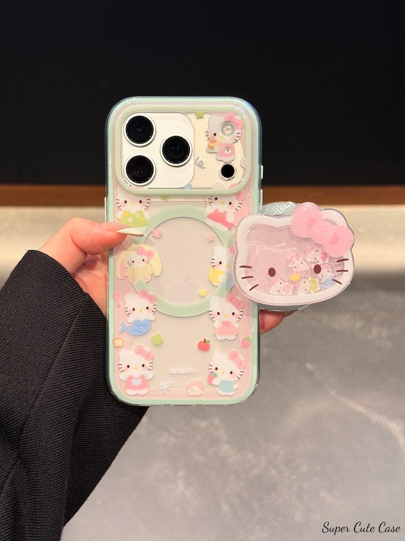 May include: A clear phone case with a light blue border and a pink Hello Kitty design. The case features multiple Hello Kitty illustrations and a matching pop-up grip. The text "Super Cute Case" is visible at the bottom right.
