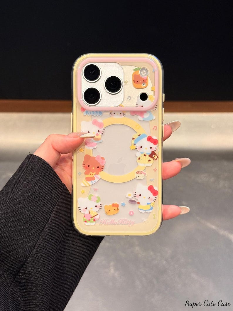 Peut inclure: Une coque de t&eacute;l&eacute;phone transparente avec un fond jaune et des motifs de personnages Hello Kitty. L'&eacute;tui a un bord de cam&eacute;ra rose et pr&eacute;sente diverses illustrations Hello Kitty, avec le texte "Hello Kitty".
