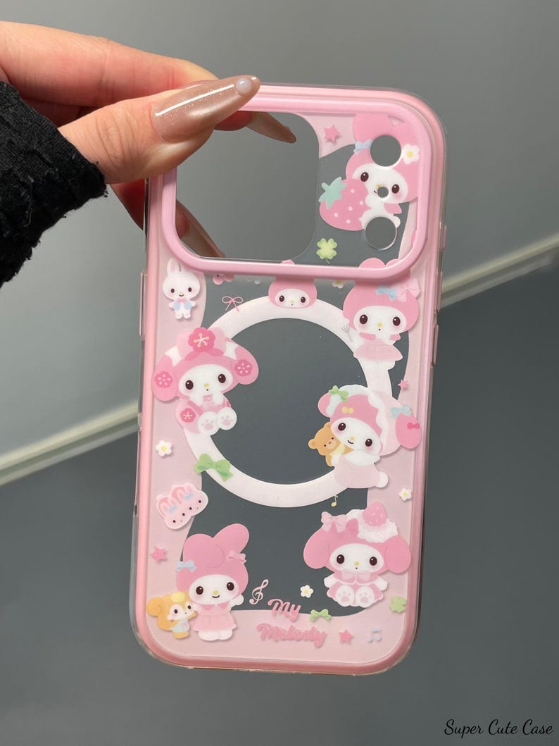 May include: Pink phone case with a clear center and a pink border. The case is decorated with cartoon characters, strawberries, and musical notes. The text "My Melody" is printed on the case.