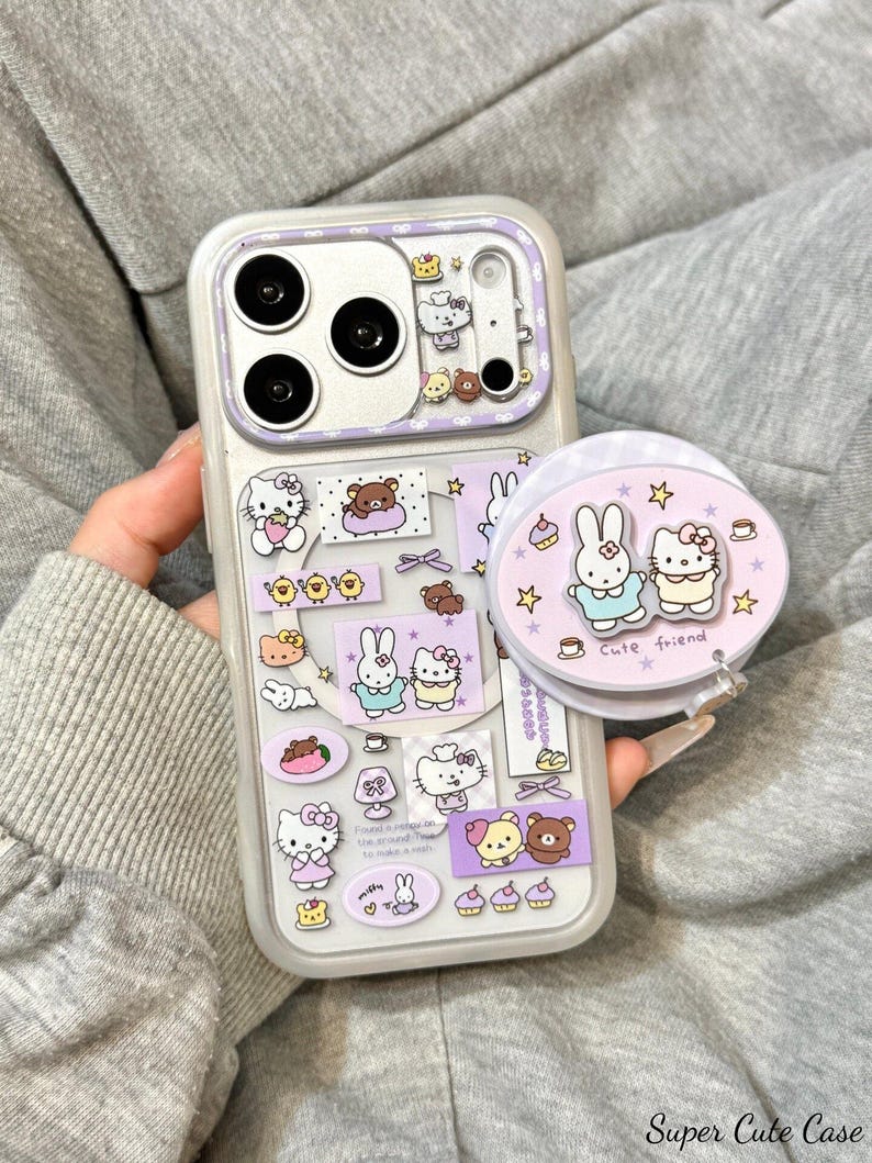 May include: A clear phone case with a purple border, featuring cartoon stickers of a cat, bear, and bunny. A matching pop-socket with the text "Cute friend" is attached. The case is held against a gray background.
