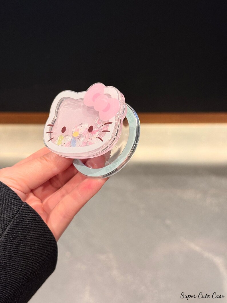 May include: A pink Hello Kitty-shaped phone case with a clear, glitter-filled center and a pink bow. The case is held in a hand. The text "Super Cute Case" is visible in the bottom right corner.