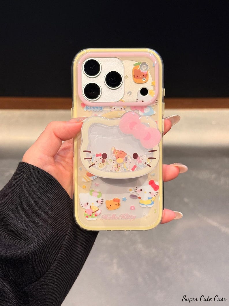 Peut inclure: Une coque de t&eacute;l&eacute;phone jaune avec des personnages Hello Kitty et un n&oelig;ud rose. La coque a un dos transparent et un bord jaune. Le design comprend diverses illustrations Hello Kitty et le texte "Hello Kitty".