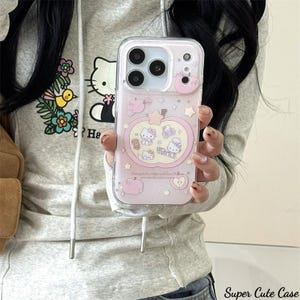 May include: Clear phone case with a pink and white design featuring cartoon characters, apples, and stars. The case has a raised pink apple accent and the text "Super Cute Case".