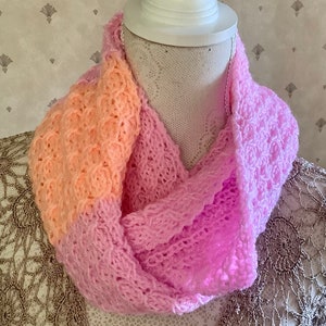 May include: A pink and peach knitted infinity scarf with a sparkly finish.