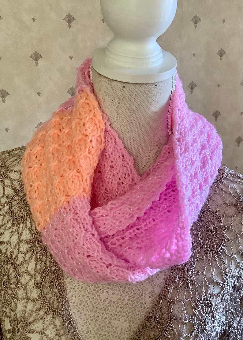 May include: A pink and peach knitted infinity scarf with a sparkly finish.