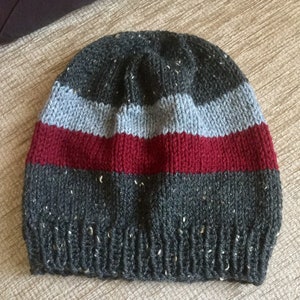 May include: A gray knit beanie with a red, gray, and blue stripe pattern.