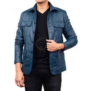 May include: A blue leather jacket with a button-up front, two chest pockets, and a collared neckline. The jacket is worn over a black V-neck shirt and black pants. The jacket appears to be a medium weight.