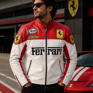 Puede incluir: Una chaqueta de cuero roja y blanca con el logotipo de Ferrari en el pecho y las mangas, un parche de Michelin y un parche de Arai Helmets. La chaqueta tiene cuello alto, cremallera frontal completa y el texto Ferrari en negro en el frente.