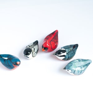 Peut inclure: Collection de cinq figurines d'oiseaux en c&eacute;ramique peintes &agrave; la main. Les oiseaux pr&eacute;sentent une vari&eacute;t&eacute; de couleurs, dont le rouge, le bleu, le noir, le blanc et le gris. Chaque oiseau a un design unique.