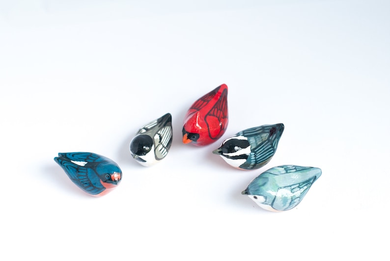 Peut inclure: Collection de cinq figurines d'oiseaux en c&eacute;ramique peintes &agrave; la main. Les oiseaux pr&eacute;sentent une vari&eacute;t&eacute; de couleurs, dont le rouge, le bleu, le noir, le blanc et le gris. Chaque oiseau a un design unique.