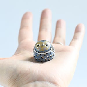 May include: A white ceramic mug with a black handle and the text "But First, Coffee" in a black, handwritten-style font. The mug is on a white surface.