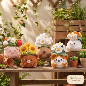 May include: A collection of handmade crochet planters shaped like animals, including a pig, bear, cat, and bunny. Each planter holds colorful crochet flowers. The planters are displayed on a wooden table with a natural background.