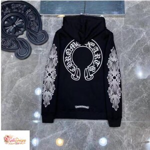 May include: Black hoodie with white ornate designs on the sleeves and back. The back features a large white emblem with the words "Chrome Hearts" in a circular design. The hoodie has a drawstring hood and a small logo near the bottom hem.