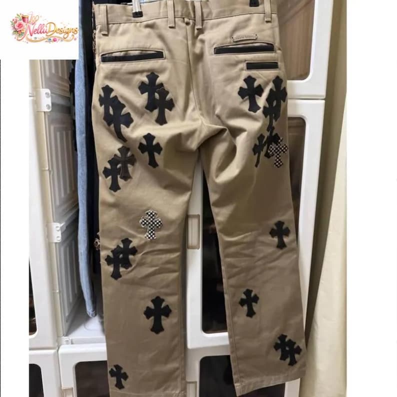 Pu&ograve; includere: Pantaloni color cachi con applicazioni a croce nere. Le croci sono di varie dimensioni e design, alcune con un motivo a scacchi. I pantaloni hanno un classico design a cinque tasche.