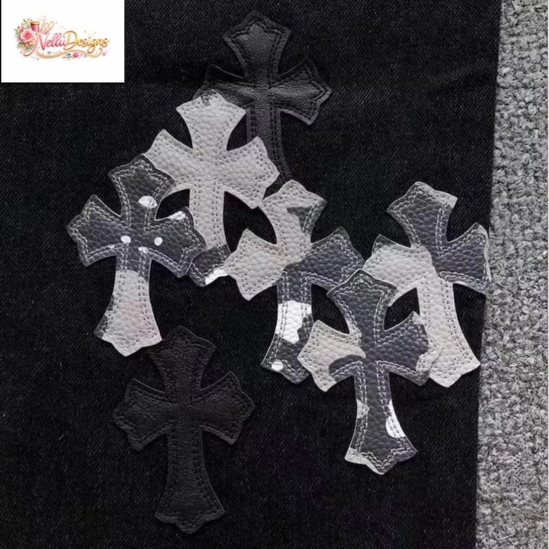 May include: A collection of decorative cross patches in various sizes and designs. The patches feature a mix of black, white, and gray colors with a textured appearance. Some crosses have a camouflage-like pattern.
