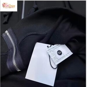 May include: Black hooded sweatshirt with a silver zipper and a white tag. The tag has text and a black string attached. The sweatshirt is a size small.