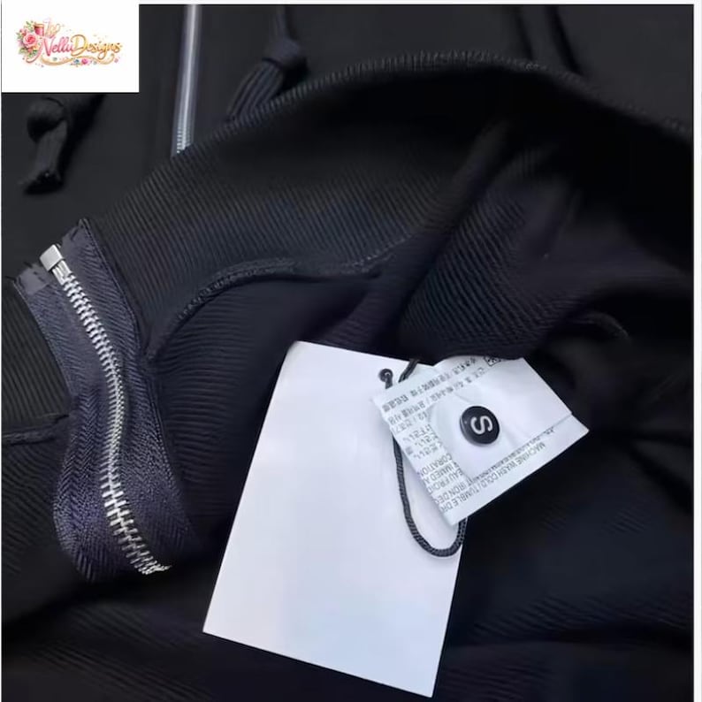 May include: Black hooded sweatshirt with a silver zipper and a white tag. The tag has text and a black string attached. The sweatshirt is a size small.
