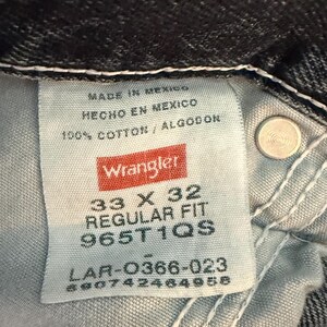 K&ouml;nnte beinhalten: Nahaufnahme eines Wrangler Jeansetiketts. Das Etikett zeigt "MADE IN MEXICO", "HECHO EN MEXICO" und "100% COTTON / ALGODON". Die Gr&ouml;&szlig;e ist 33 x 32, Regular Fit, mit einem Produktcode.