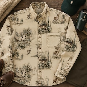 May include: A long-sleeve button-down shirt in a light beige colour featuring an all-over dark brown print of deer and forest landscapes. The shirt includes a single chest pocket, a button-down collar, and a Woods & Water label at the neck.