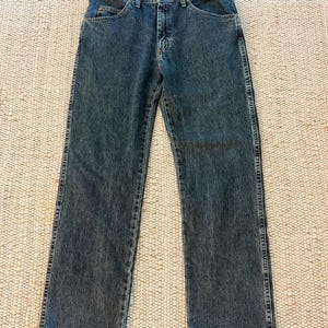 K&ouml;nnte beinhalten: Dunkelblaue Jeans mit klassischem F&uuml;nf-Taschen-Design. Die Jeans haben einen geraden Beinverlauf und einen Knopf- und Rei&szlig;verschluss. Der Denim hat ein leicht verwaschenes Aussehen, und die N&auml;hte sind entlang der N&auml;hte und Taschen sichtbar.