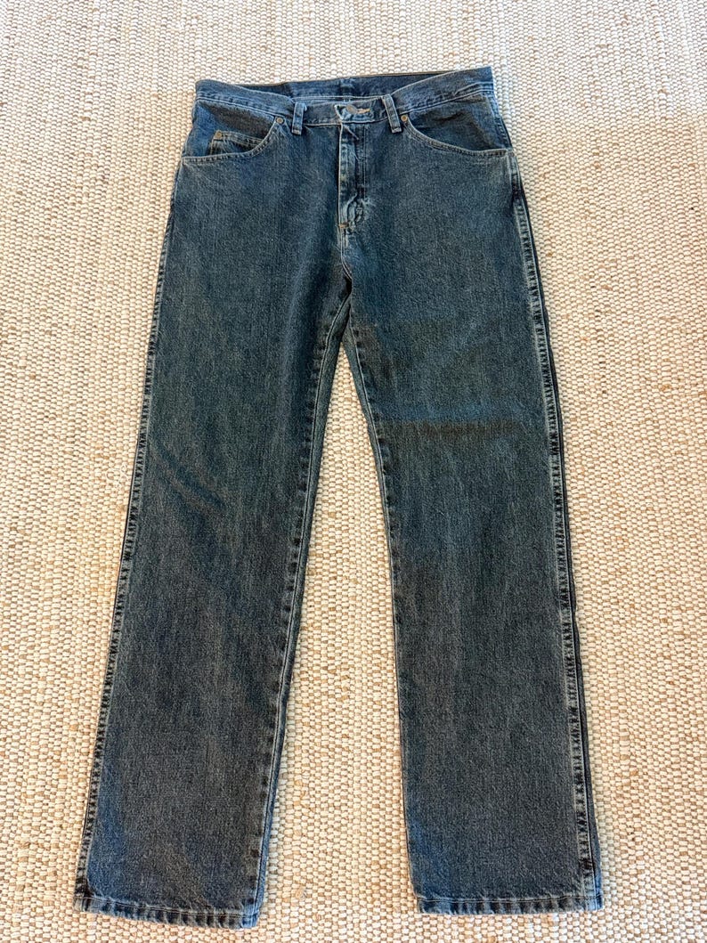 K&ouml;nnte beinhalten: Dunkelblaue Jeans mit klassischem F&uuml;nf-Taschen-Design. Die Jeans haben einen geraden Beinverlauf und einen Knopf- und Rei&szlig;verschluss. Der Denim hat ein leicht verwaschenes Aussehen, und die N&auml;hte sind entlang der N&auml;hte und Taschen sichtbar.
