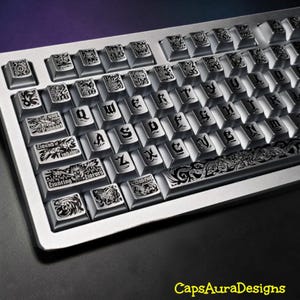 May include: A silver mechanical keyboard featuring custom keycaps with intricate black engraved illustrations and gothic-style lettering. The spacebar displays ornate scrollwork, while specific keys feature text including Hound of Tindalos.