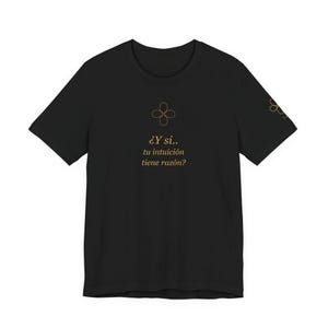 May include: Black t-shirt with gold text and a four-leaf clover design. The text reads "¿Y si.. tu intuición tiene razón?" on the front. A smaller clover design is on the sleeve. A casual tee for everyday wear.