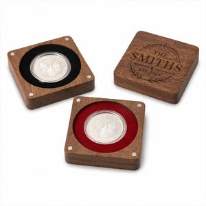 Pode incluir: Três caixas de exibição de moedas de madeira. Duas caixas contêm moedas de prata com forro de veludo preto e vermelho. A terceira caixa tem uma tampa de madeira com o texto gravado "THE SMITHS EST. 2024" em um design circular.