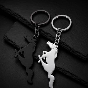 Peut inclure: Deux porte-clés en métal représentant la silhouette d'un cheval cabré. L'un des porte-clés présente une finition noire mate, tandis que l'autre est doté d'une finition argentée polie. Chacun comprend un anneau fendu circulaire fixé par une chaînette.