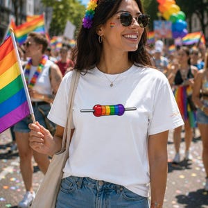 May include: A white t-shirt featuring a rainbow resistor design. The image shows a person at a Pride parade, holding a rainbow flag. The person is wearing sunglasses and a floral crown. The text at the bottom of the image says, "This image was created using AI for illustration purposes."