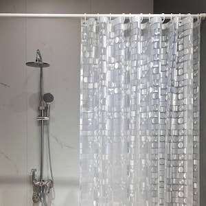 May include: A translucent shower curtain featuring a repeating geometric pattern of circles and rectangles in a semi-opaque white finish. The curtain hangs from a white rod with integrated rings, positioned next to a chrome shower fixture.