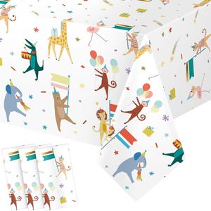 May include: White tablecloth and matching napkins with a circus animal theme. The tablecloth features illustrations of a giraffe, elephant, monkey, lion, and other animals. The napkins have a gold and teal border.